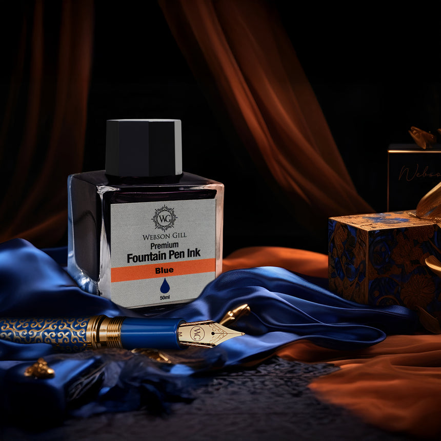 A Webson Gill 'Ink in a Bottle' Fountain Pen Refill—blue ink, compatible with all fountain pens—rests beside an ornate fountain pen on blue and orange fabric, creating a striking composition.