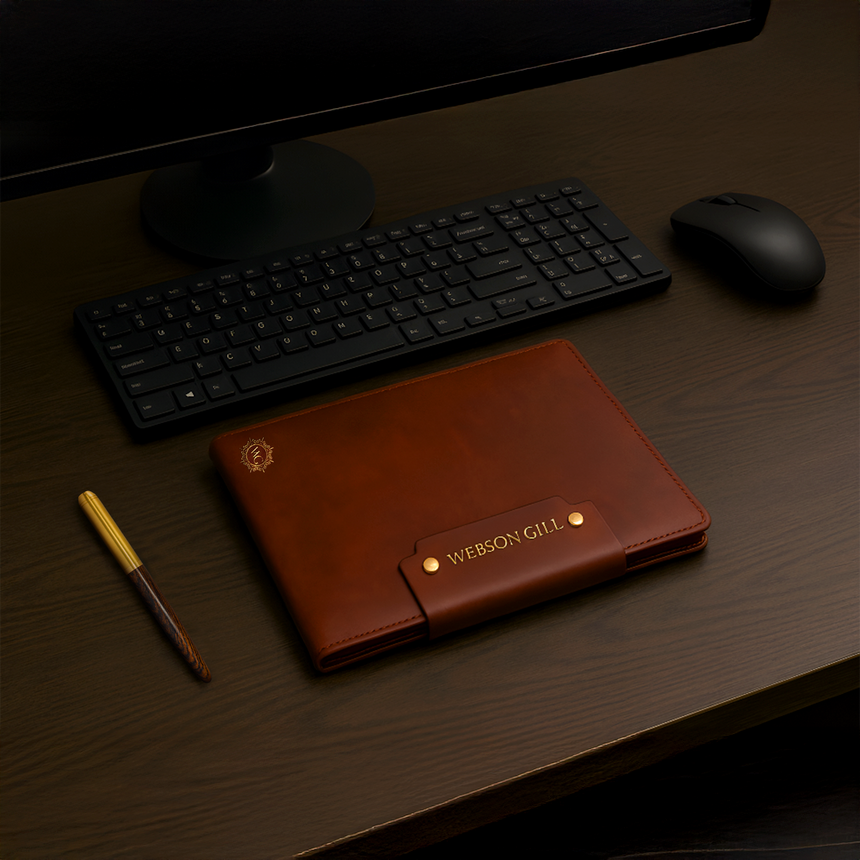 A Leather Writing Notebook from Webson Gill rests on a desk beside a keyboard, mouse, and fountain pen notebook.