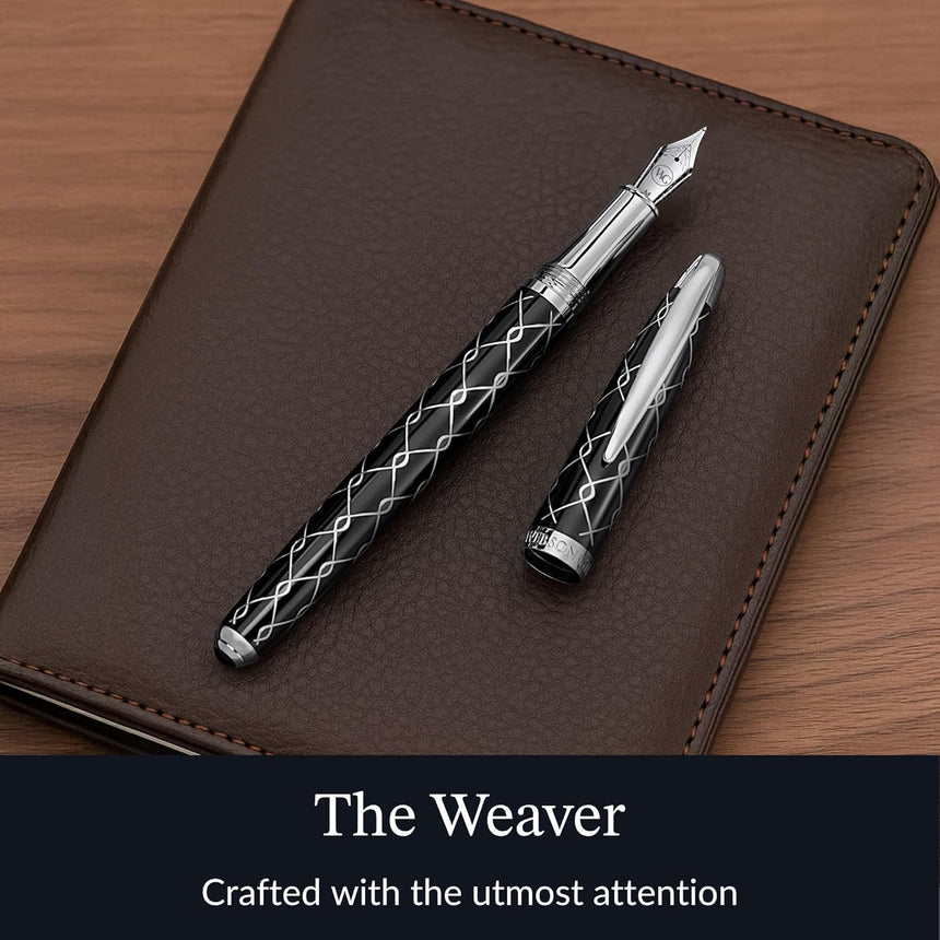 The WG ‘The Weaver’ Everyday Fountain Pen, featuring a silver lattice design and stainless steel medium nib, lies atop a brown leather notebook, promising a smooth writing experience.