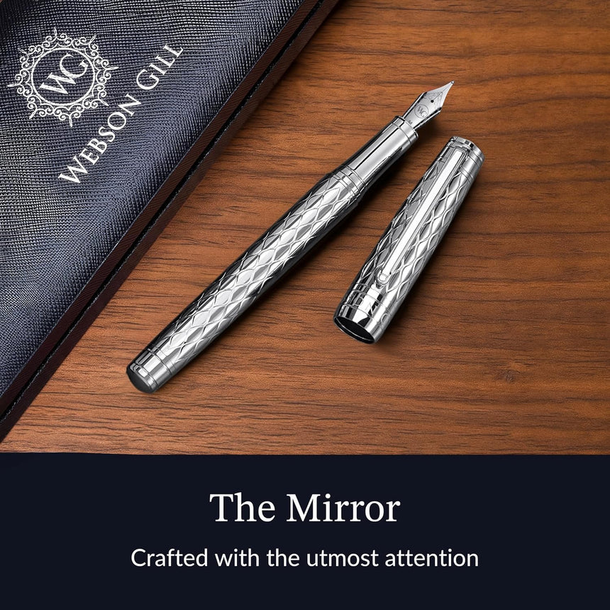 The WG ‘The Mirror’ Everyday Fountain Pen, featuring a patterned cap and stainless steel nib, rests on a wooden surface next to its case.