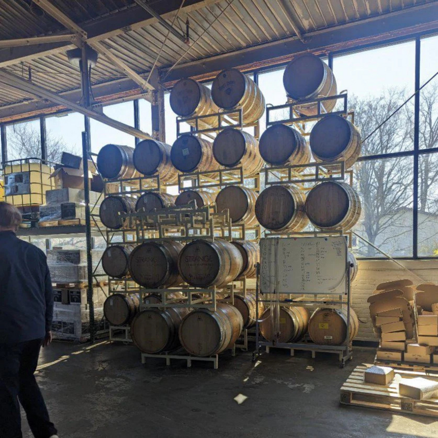 Sunlight filters through warehouse racks of wood barrels, reminiscent of the reclaimed oak used to craft the Webson Gill 'Bourbon Barrel' Premium Fountain Pen.