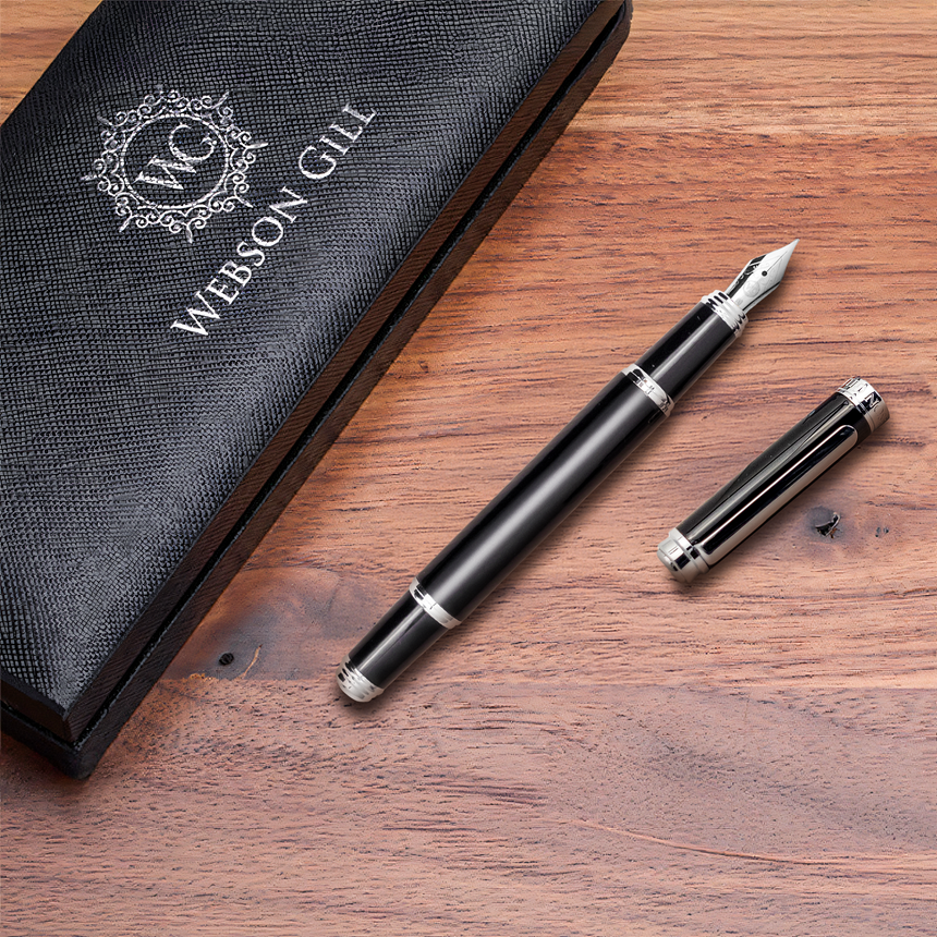 'The Mogul' Premium Fountain Pen by Webson Gill, featuring silver accents and a stainless steel nib with its cap off, rests next to a Webson Gill case on a wooden surface.
