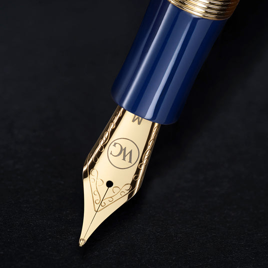 Close-up of The Regal Fountain Pen nib by Webson Gill, featuring ornate gold brass filigree and a blue pen body on a black surface—ideal for fountain pen collectors.