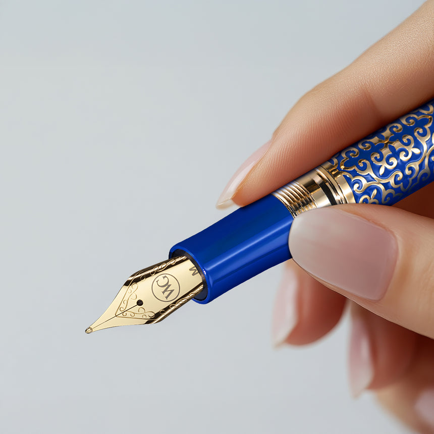 A hand holds 'The Regal' Premium Fountain Pen by Webson Gill—an ornate blue and gold luxury pen with a decorative nib, perfect for fountain pen collectors.