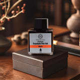 A jar of Webson Gill Ink Universal Fountain Pen Refill (Blue) by Webson Gill rests on a brown box in a warmly lit study, ideal for fountain pens, with books in the background.