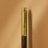 Close-up of the Webson Gill Prestige Edition Fountain Pen, featuring a gold and wood design with "WEBSON GILL" engraved on the clip and an iridium nib, set against a beige background.