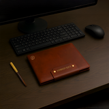 A Leather Writing Notebook from Webson Gill rests on a desk beside a keyboard, mouse, and fountain pen notebook.