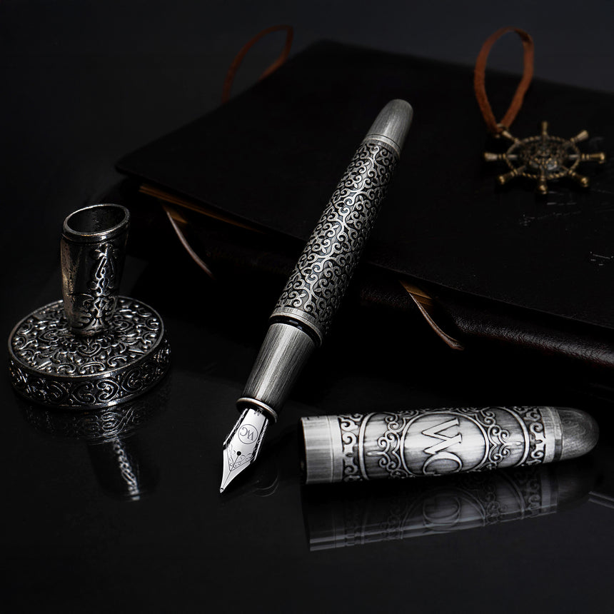 The Webson Gill Admiral Fountain Pen, paired with its holder, rests elegantly on a dark surface with a black journal in the background—a refined luxury writing instrument for discerning writers.