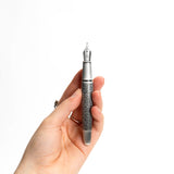 A hand holds the Webson Gill Admiral Fountain Pen, featuring ornate silver craftsmanship and a decorative pattern, set against a white background.