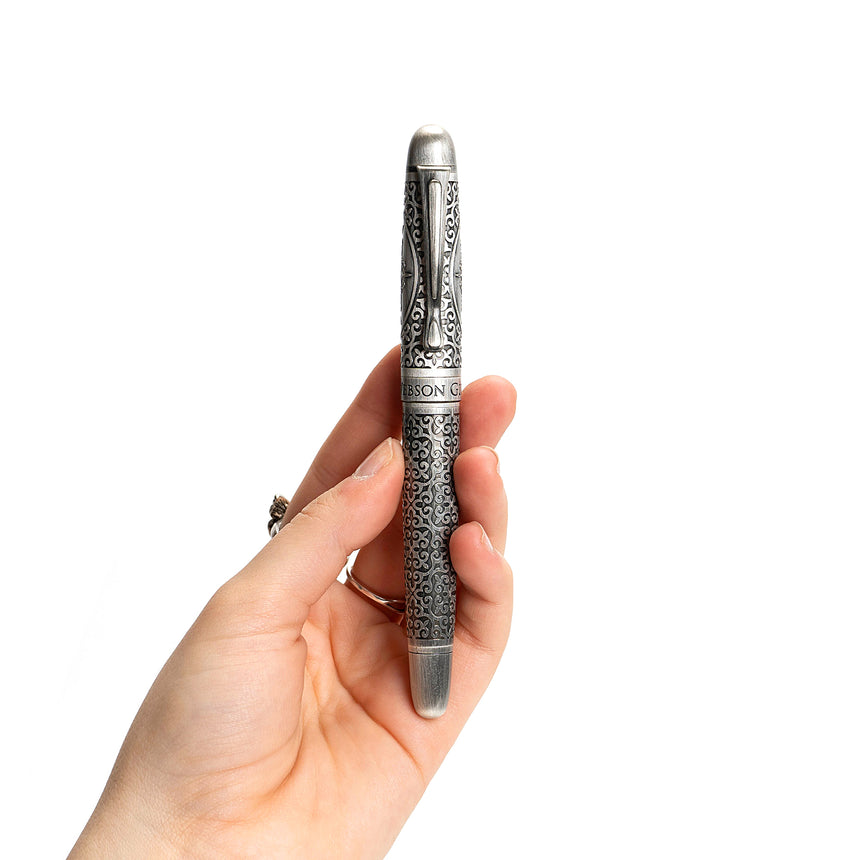 A hand holds the Admiral Fountain Pen by Webson Gill, an ornate antique-style silver pen with intricate decorative patterns, exemplifying a luxury writing instrument.