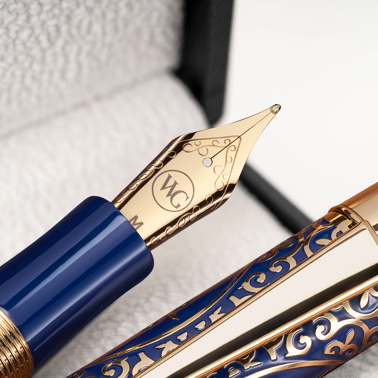 A close-up of The Regal Fountain Pen by Webson Gill shows its ornate gold and blue nib with elegant engravings—an ideal piece for fountain pen collectors.