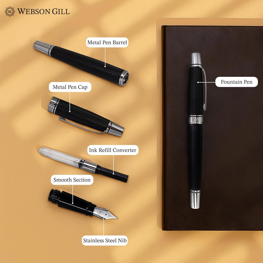 A disassembled WG 'Show Up' Everyday Fountain Pen, black with a stainless steel medium nib and diamond guilloché pattern, is shown next to a closed brown notebook on a yellow surface.
