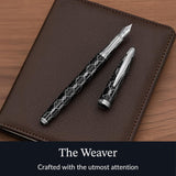 The WG ‘The Weaver’ Everyday Fountain Pen, featuring a silver lattice design and stainless steel medium nib, lies atop a brown leather notebook, promising a smooth writing experience.