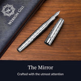 The WG ‘The Mirror’ Everyday Fountain Pen, featuring a patterned cap and stainless steel nib, rests on a wooden surface next to its case.