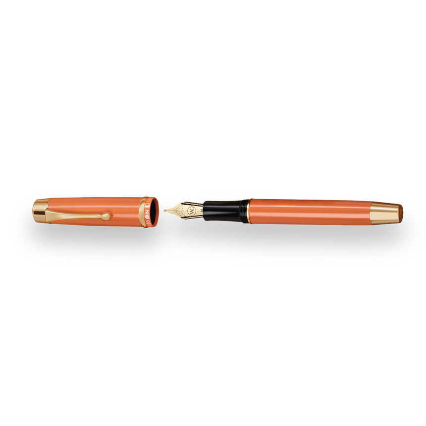 The Muse Fountain Pen by Webson Gill is an orange pen with an ergonomic design, featuring a gold-plated nib and a matching cap, both accented with gold.