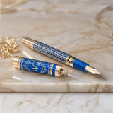 The Regal Fountain Pen by Webson Gill features a blue and gold design with a gold brass filigree cap, shown resting on marble—a stunning addition for any fountain pen collector.